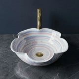 Decorative sink with a gold faucet on a dark surface