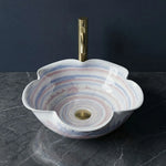 Decorative sink with a gold faucet on a dark surface