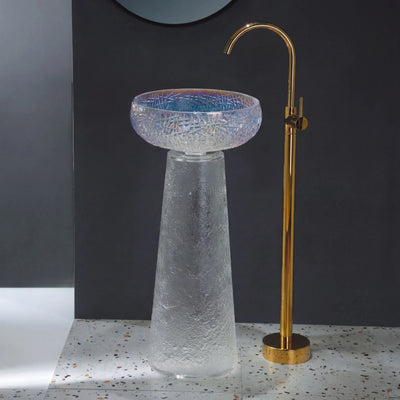 Glass sink with gold faucet against a dark wall