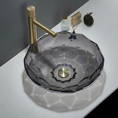 Glass sink with gold faucet on a white countertop