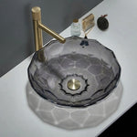 Glass sink with gold faucet on a white countertop