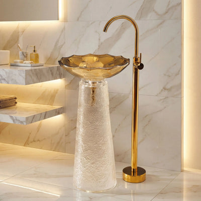 Bathroom sink with gold faucet against a marble wall