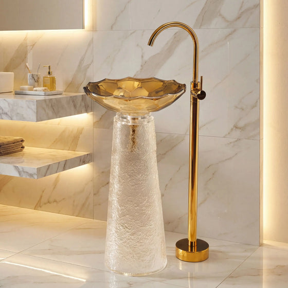 Bathroom sink with gold faucet against a marble wall