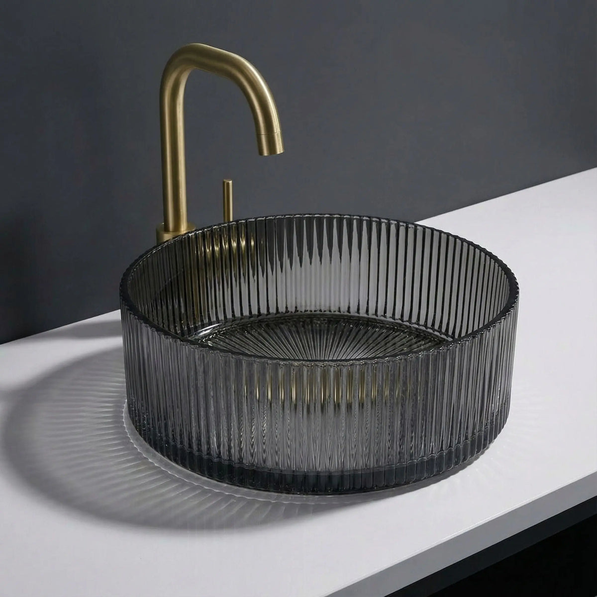 Black ribbed sink with gold faucet on a white countertop against a dark background