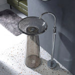 Modern freestanding bathtub with glass bowl and chrome faucet in a bathroom setting.