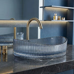 Clear glass sink with gold faucet in a modern bathroom setting