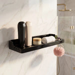 Black wall-mounted shower caddy with toiletries on a marble wall