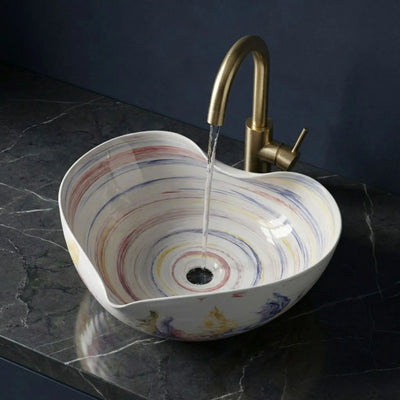 Multicolored sink with a gold faucet on a dark marble countertop