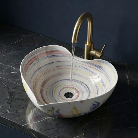 Multicolored sink with a gold faucet on a dark marble countertop