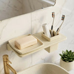 Bathroom shelf with soap, toothbrushes, and a plant on a marble wall background