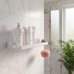 Bathroom with white shelves holding skincare products, a shower, and a plant.
