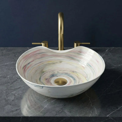 Marbled patterned sink with gold faucet on a dark surface
