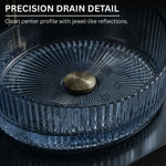Clear glass bowl with gold center on a dark background, highlighting precision drain detail.