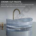 Clear glass sink with gold faucet on a gray background