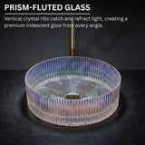 Prism-fluted glass sink with iridescent glow on a dark background