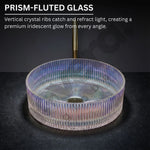Prism-fluted glass sink with iridescent glow on a dark background