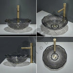 Gray glass sink with gold faucet on a white surface against a dark background