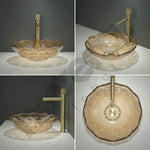 Glass sink with gold faucet on a gray background