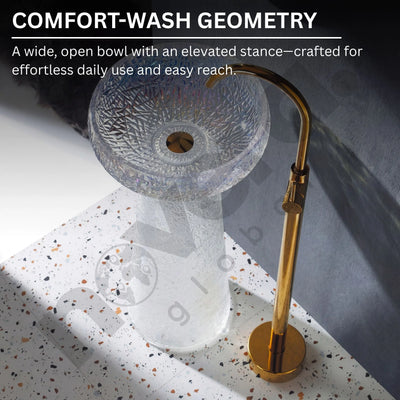 Clear glass sink with gold faucet on a speckled countertop