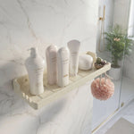 Bathroom shelf with skincare products and a plant in a modern bathroom setting