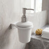 White soap dispenser with silver pump on a bathroom wall