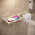 Bathroom shelf with phone holder and toilet paper roll on tiled wall