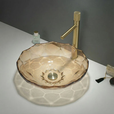 Glass sink with gold faucet on a white surface