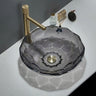 Glass sink with gold faucet on a white countertop