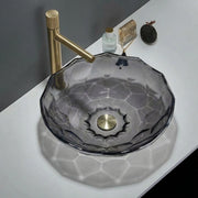 Glass sink with gold faucet on a white countertop