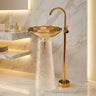 Bathroom sink with gold faucet against a marble wall
