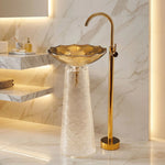 Bathroom sink with gold faucet against a marble wall