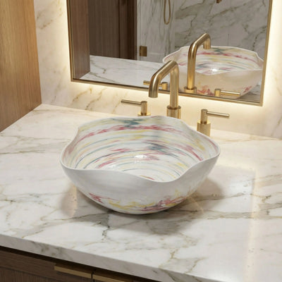 Decorative sink with artistic patterns on a marble countertop with gold fixtures.