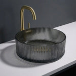 Black ribbed sink with gold faucet on a white countertop against a dark background