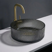 Black ribbed sink with gold faucet on a white countertop against a dark background