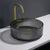 Black ribbed sink with gold faucet on a white countertop against a dark background