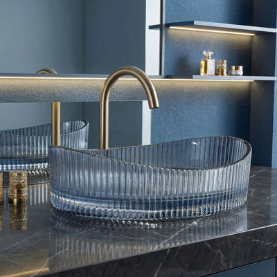 Clear glass sink with gold faucet in a modern bathroom setting