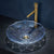 Clear glass sink with gold faucet against a dark background