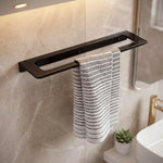 Black towel rack with a striped towel on a marble wall in a bathroom.