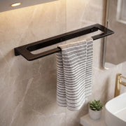 Black towel rack with a striped towel on a marble wall in a bathroom.