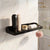 Black wall-mounted shower caddy with toiletries on a marble wall