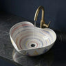 Multicolored sink with a gold faucet on a dark marble countertop