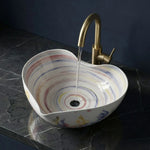 Multicolored sink with a gold faucet on a dark marble countertop