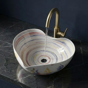 Multicolored sink with a gold faucet on a dark marble countertop