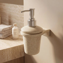 Beige soap dispenser mounted on a bathroom wall with a neutral color scheme.