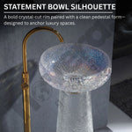 Crystal bowl sink with gold faucet against a dark background