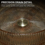 Close-up of a metallic drain with textured rim and central circular feature.