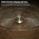 Close-up of a metallic drain with textured rim and central circular feature.