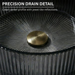 Close-up of a precision drain detail with a gold center and textured black surface.
