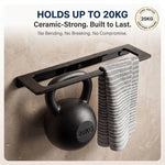 Black towel rack holding a kettlebell and towel on a beige wall.