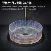 Prism-fluted glass sink with iridescent glow on a dark background